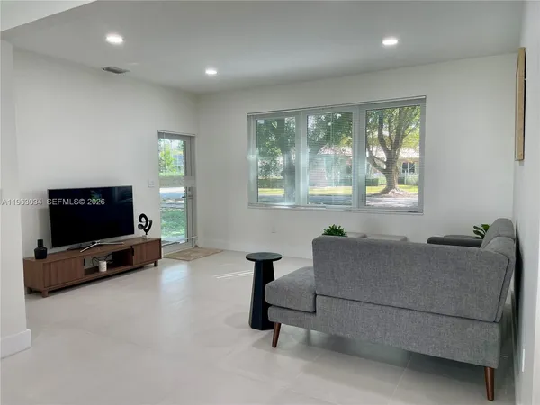 a living room with furniture a flat screen tv and a window
