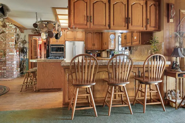 a kitchen with stainless steel appliances granite countertop a stove a sink and white cabinets with wooden floor