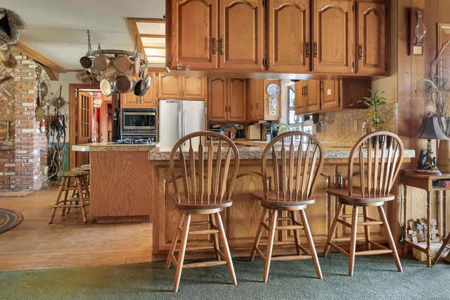 a kitchen with stainless steel appliances granite countertop a stove a sink and white cabinets with wooden floor