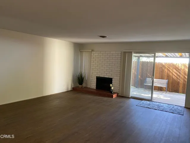 an empty room with wooden floor fireplace and windows