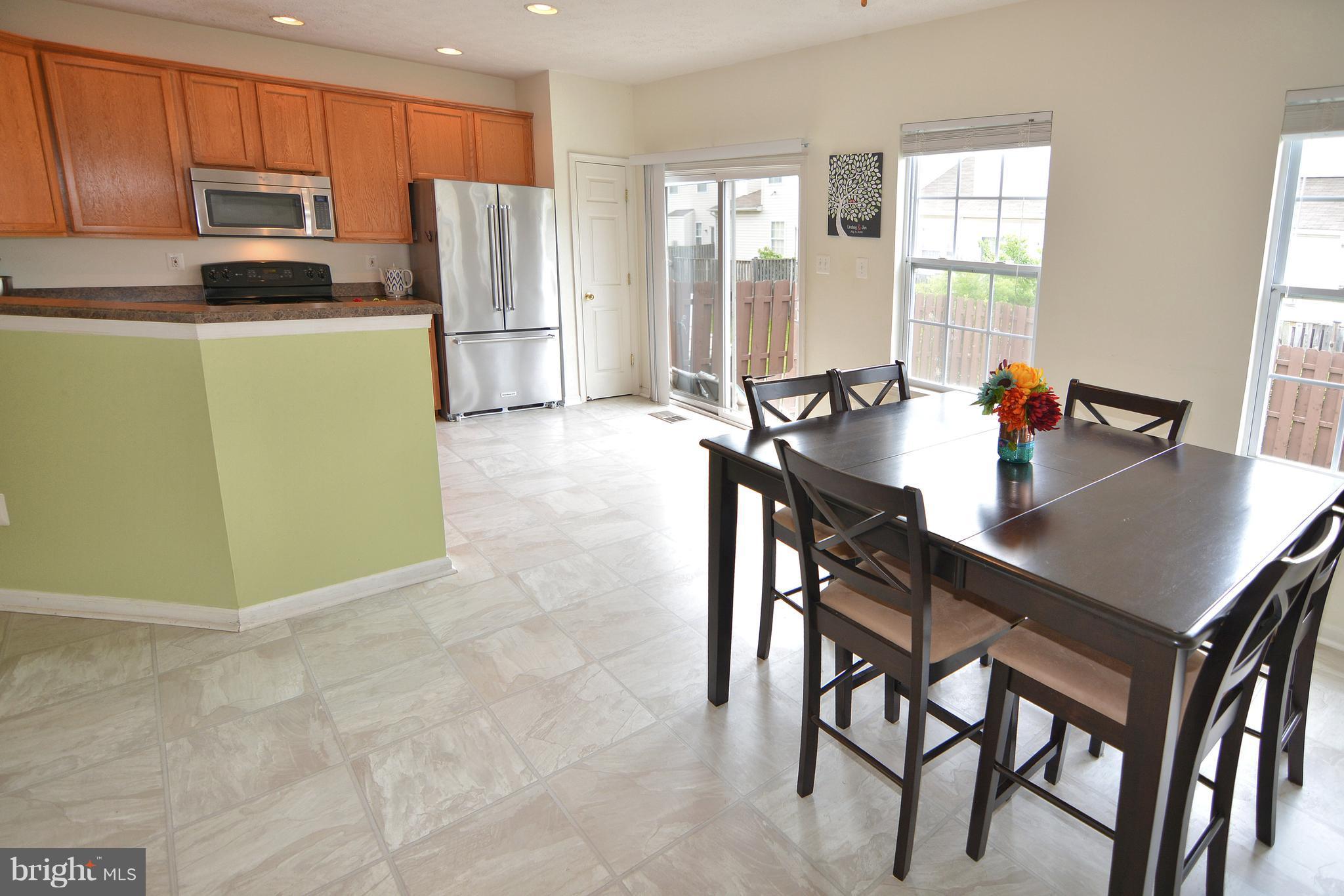 9722 Langley Road Baltimore, MD 21220 - Photo 7 of 30 a kitchen with stainless steel appliances a refrigerator a stove a dining table and chairs