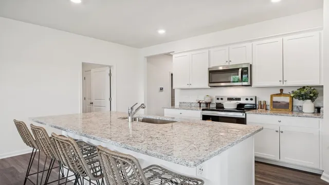 a kitchen with kitchen island granite countertop a sink white cabinets and stainless steel appliances