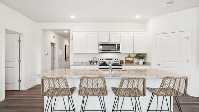 a kitchen with stainless steel appliances granite countertop a table chairs microwave and sink