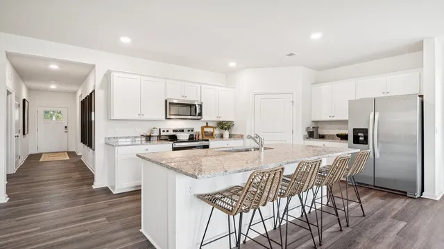 a kitchen with stainless steel appliances granite countertop a refrigerator a stove top oven a sink dishwasher and white cabinets with wooden floor
