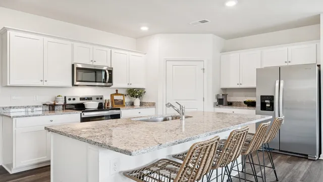 a kitchen with granite countertop a sink a counter top space appliances and cabinets
