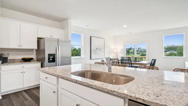 a kitchen with granite countertop a sink a counter top space cabinets and stainless steel appliances