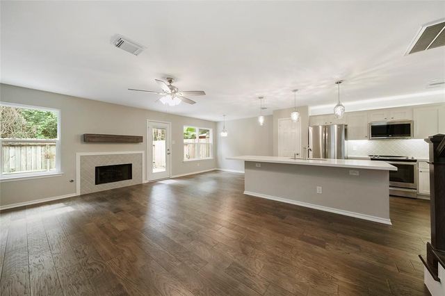 a view of kitchen and empty room with wooden floor and a fireplace