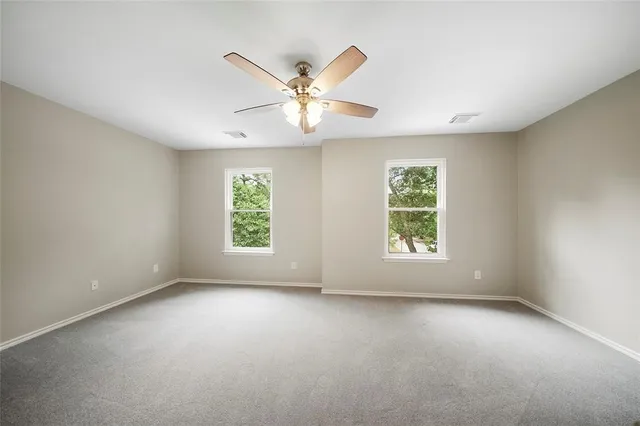 an empty room with windows and fan