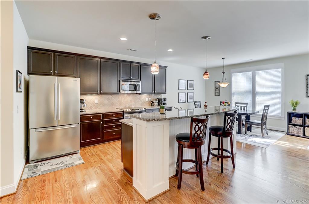 3422 Richard's Crossing Fort Mill, SC 29708 - Photo 12 of 48 a kitchen with stainless steel appliances granite countertop a refrigerator a stove a sink a dining table and chairs with wooden floor