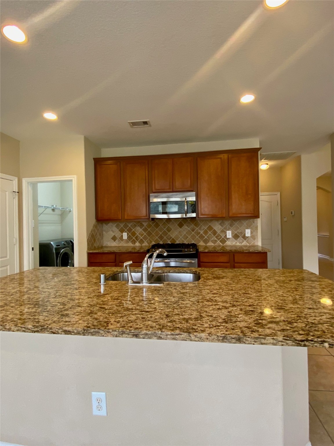 15 Sagamore Ridge Place The Woodlands, TX 77389 - Photo 16 of 39 a kitchen with kitchen island granite countertop a stove a sink a microwave a refrigerator and cabinets