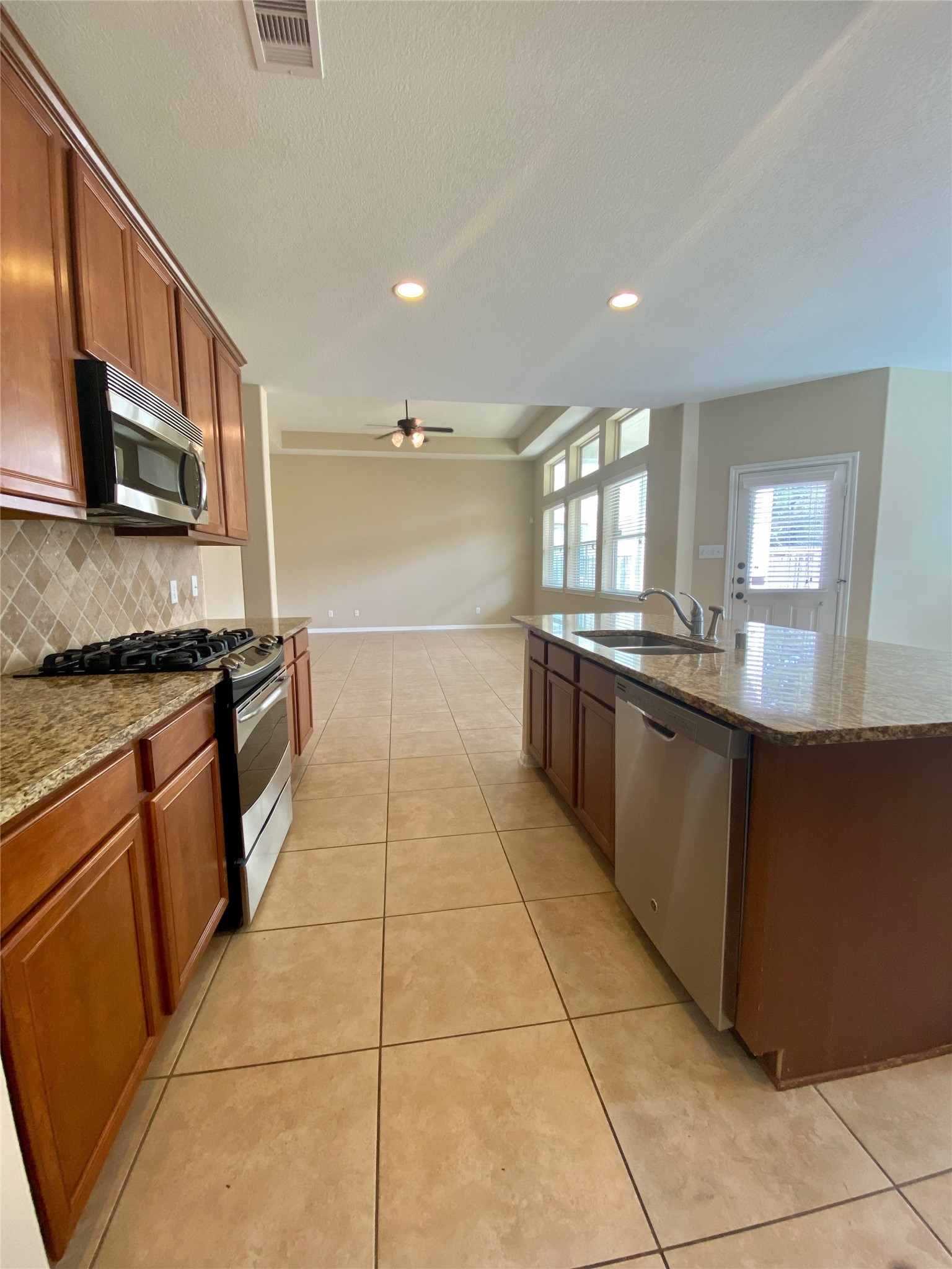 15 Sagamore Ridge Place The Woodlands, TX 77389 - Photo 17 of 39 a large kitchen with stainless steel appliances granite countertop a stove a sink and a microwave