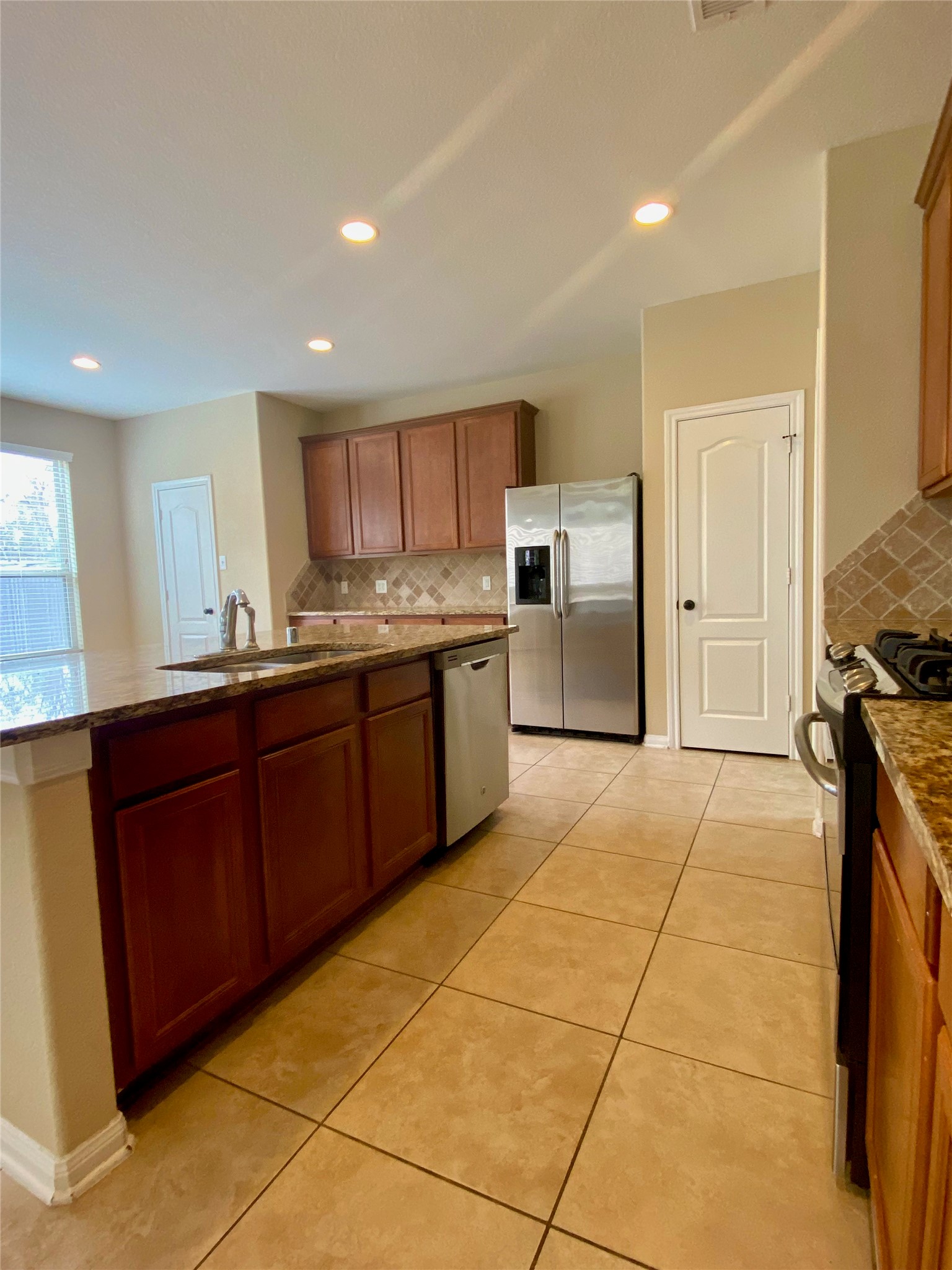 15 Sagamore Ridge Place The Woodlands, TX 77389 - Photo 18 of 39 a kitchen with stainless steel appliances granite countertop a stove a sink and a refrigerator