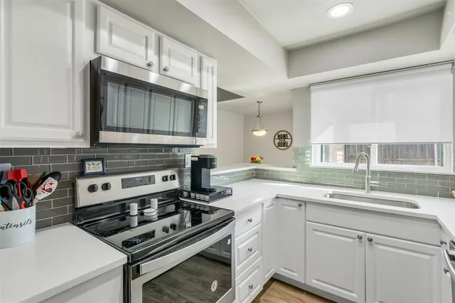 a kitchen with stainless steel appliances a sink dishwasher stove and white cabinets