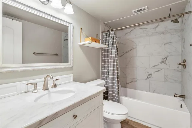 a bathroom with a granite countertop sink a toilet and shower