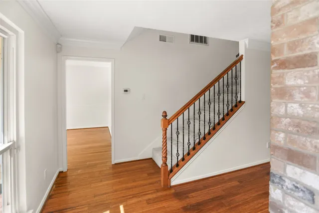 a view of a hallway with wooden floor and staircase