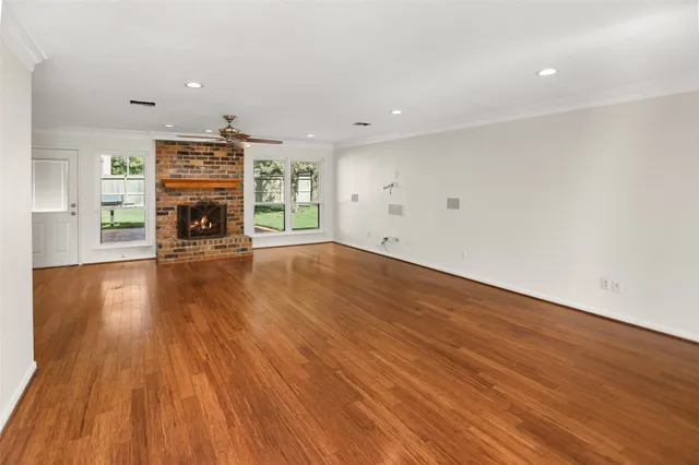 an empty room with wooden floor a fireplace and windows