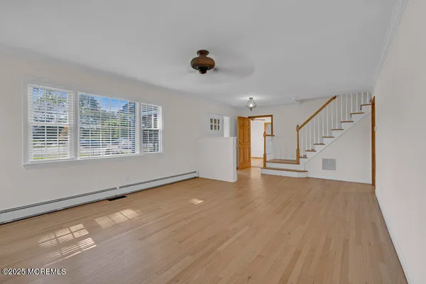 a view of an empty room with a window and wooden floor