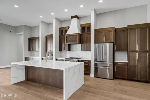 a kitchen with kitchen island granite countertop a refrigerator and a stove top oven