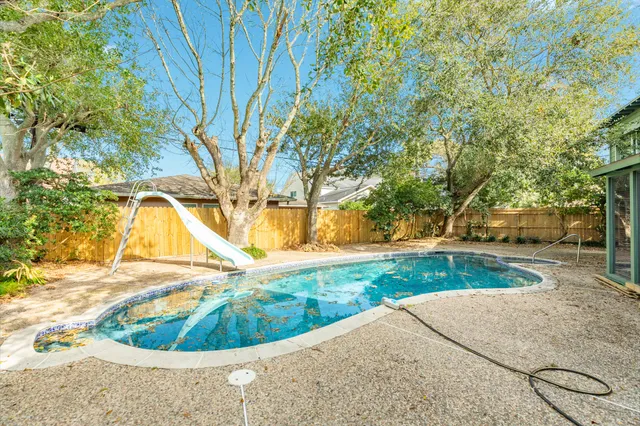 a view of a swimming pool in a yard with palm trees