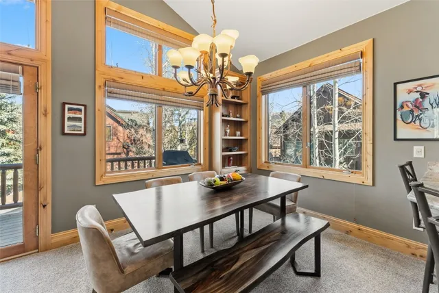 a view of a dining room with furniture a chandelier and a window