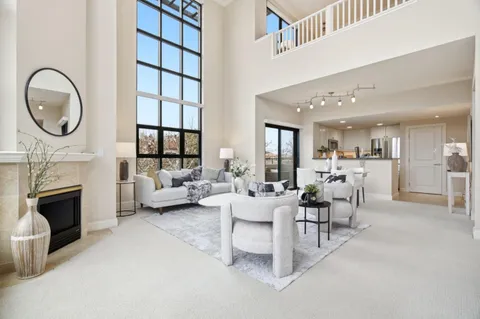 a living room with furniture a fireplace a flat screen tv and windows
