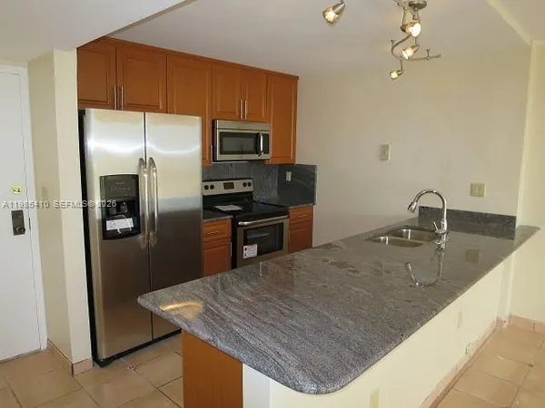 a kitchen with stainless steel appliances granite countertop a sink a refrigerator a stove a microwave and island