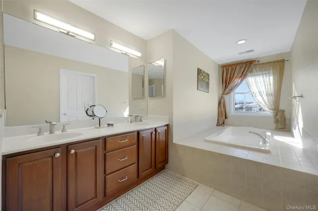 a spacious bathroom with a double vanity sink a mirror and a bathtub