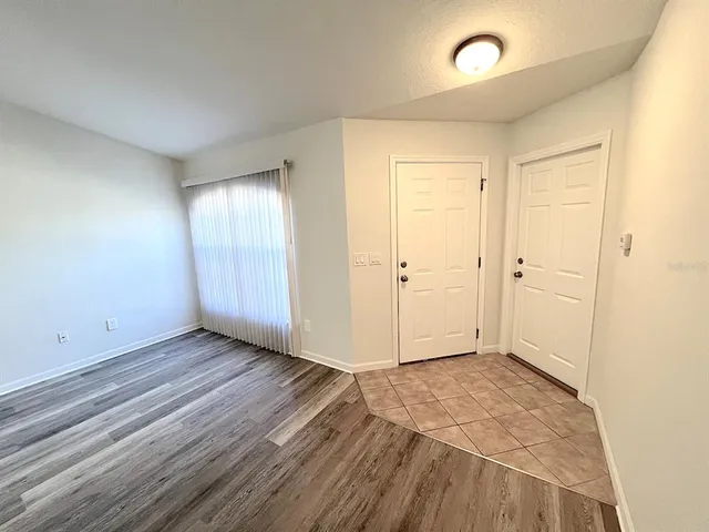 a view of an empty room with window and wooden floor