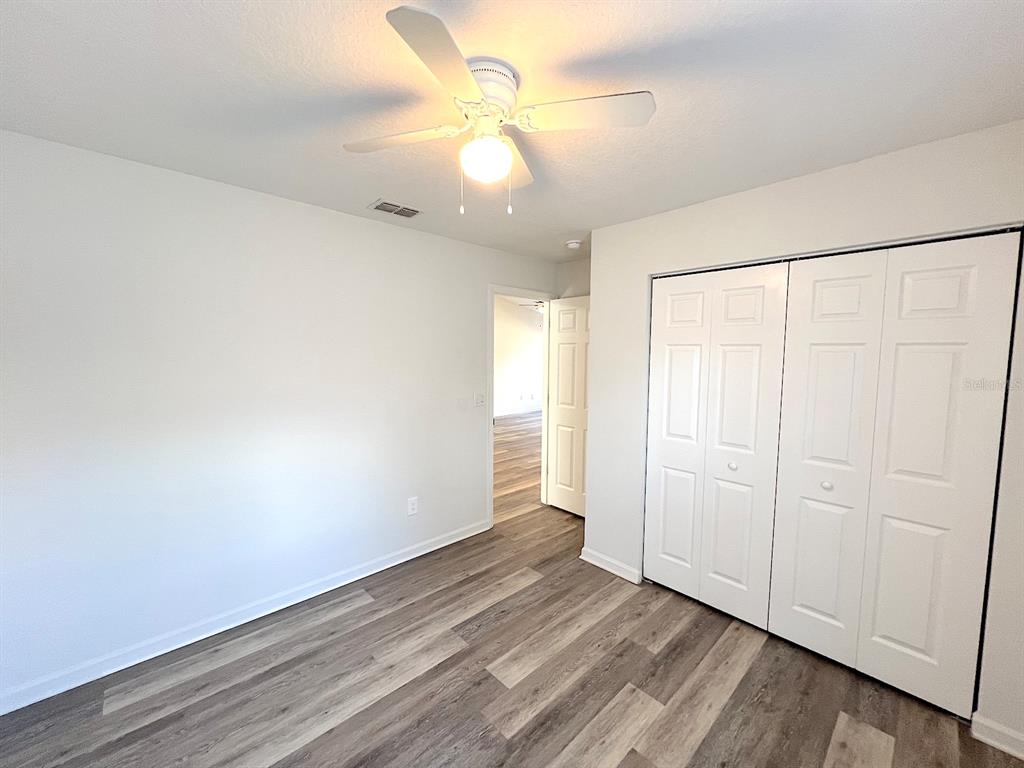 20 Plateau Lane, Unit A Palm Coast, FL 32164 - Photo 25 of 37 an empty room with wooden floor and fan