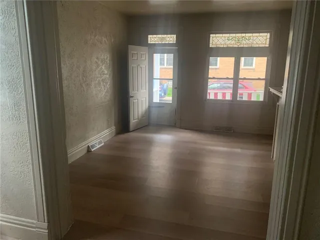an empty room with wooden floor and windows