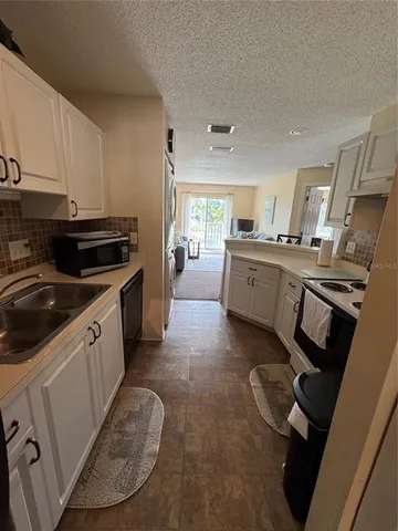 a kitchen with granite countertop a sink stove and cabinets