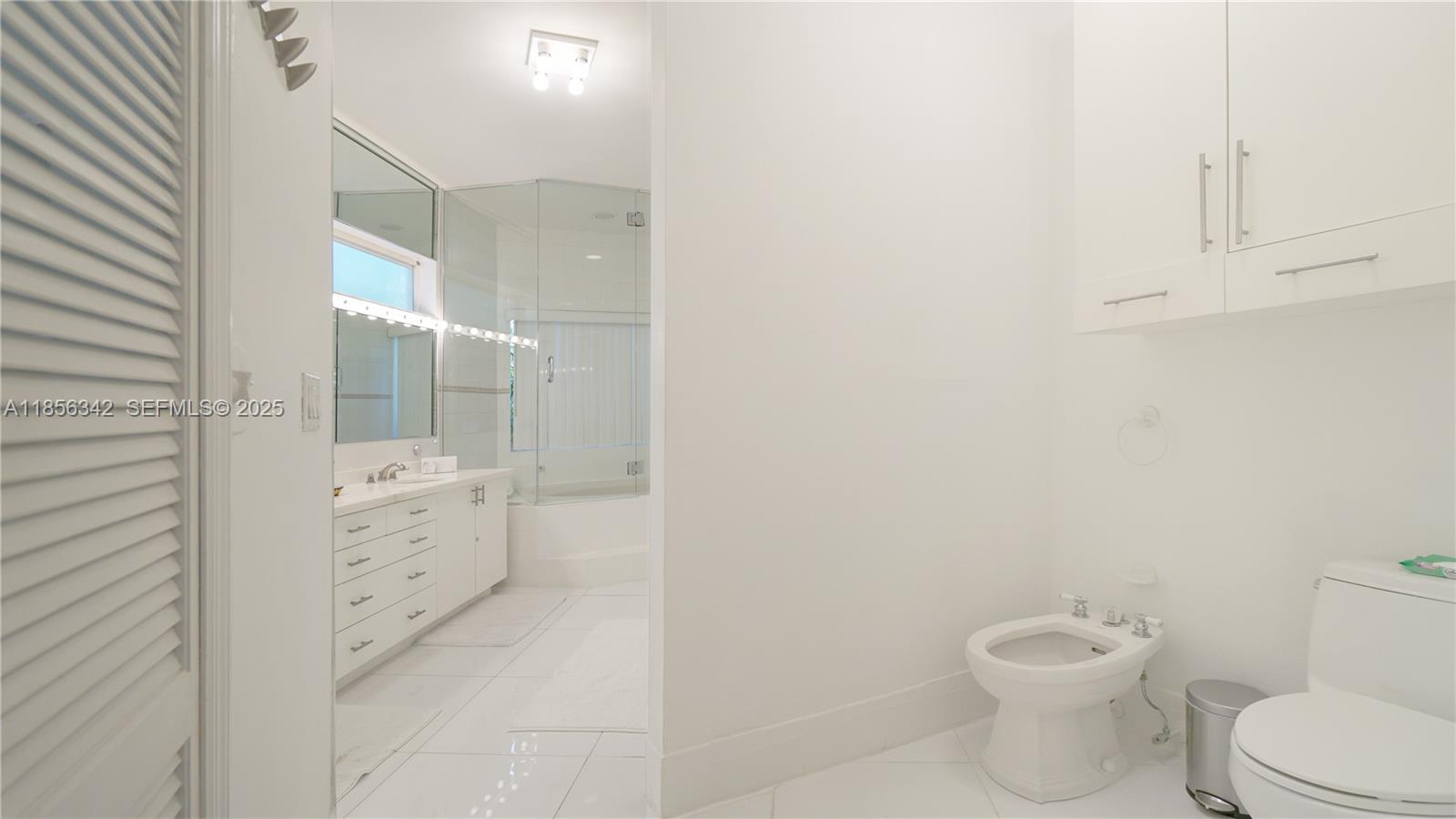691 Ridgewood Road Key Biscayne, FL 33149 - Photo 28 of 67 a bathroom with a granite countertop toilet a sink and mirror