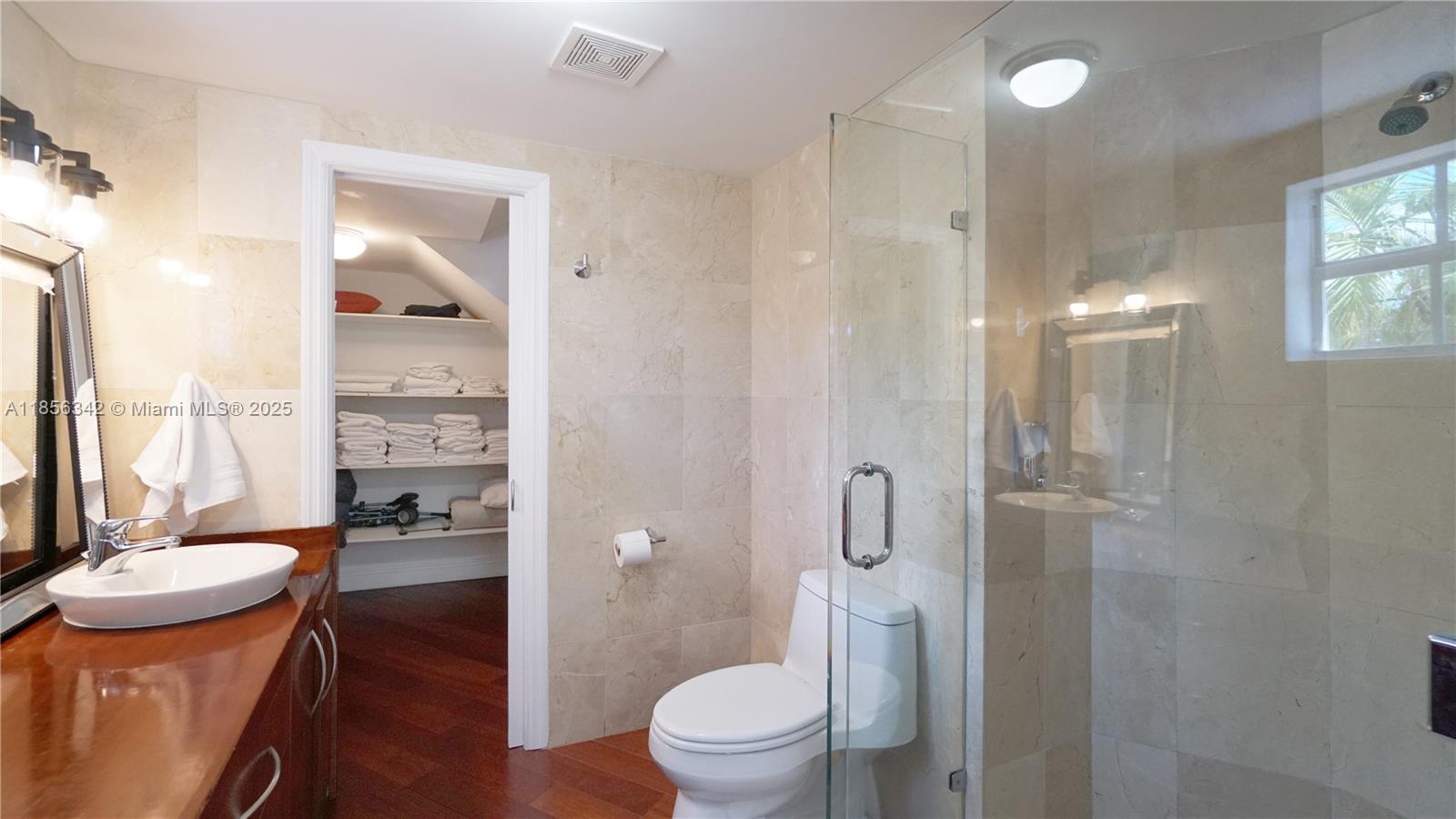 691 Ridgewood Road Key Biscayne, FL 33149 - Photo 37 of 67 a bathroom with a granite countertop toilet a sink a mirror and shower