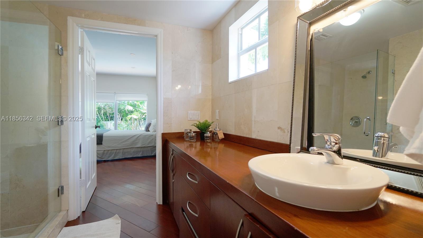 691 Ridgewood Road Key Biscayne, FL 33149 - Photo 38 of 67 a en suite bathroom with a double vanity sink and mirror