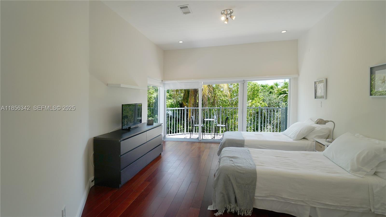 691 Ridgewood Road Key Biscayne, FL 33149 - Photo 50 of 67 a bedroom with a balcony a bed and a large window with outer view