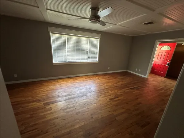 a view of an empty room with window and wooden floor