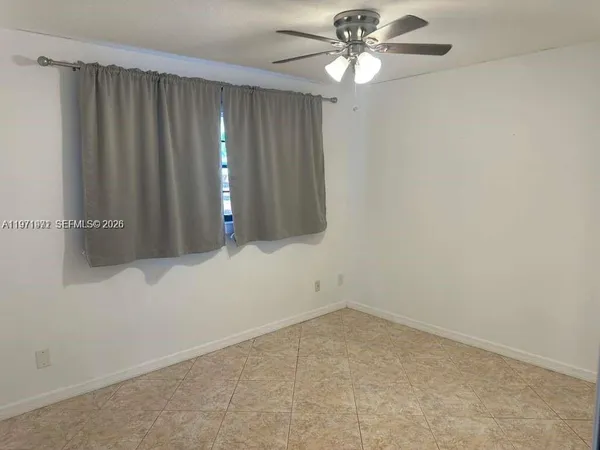 a view of an empty room with chandelier fan