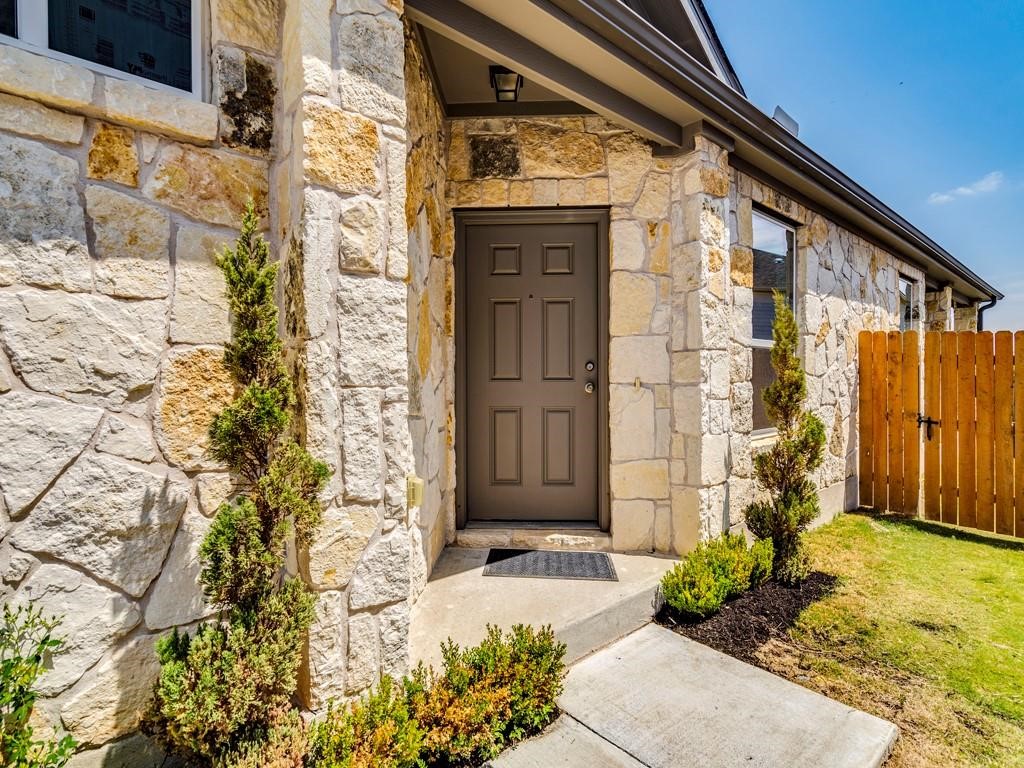 4210 Birdwatch Loop, Unit 2 Pflugerville, TX 78660 - Photo 7 of 31 A welcoming entry framed by decorative shrubs and a rustic stone facade.