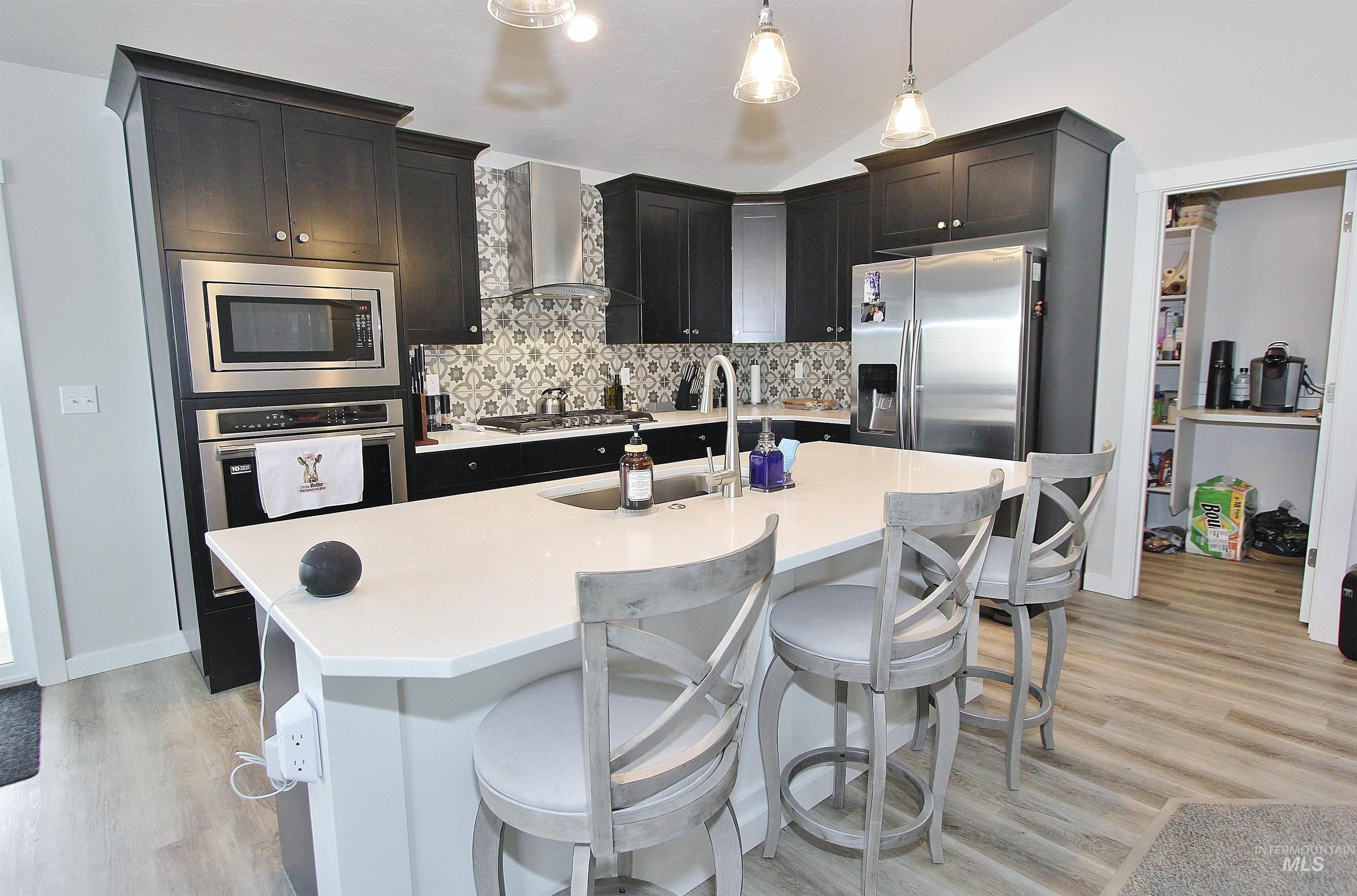1211 Mahogany Street Parma, ID 83660 - Photo 5 of 22 Kitchen with vaulted ceiling, stainless steel appliances, an island with sink, a kitchen breakfast bar, and decorative backsplash