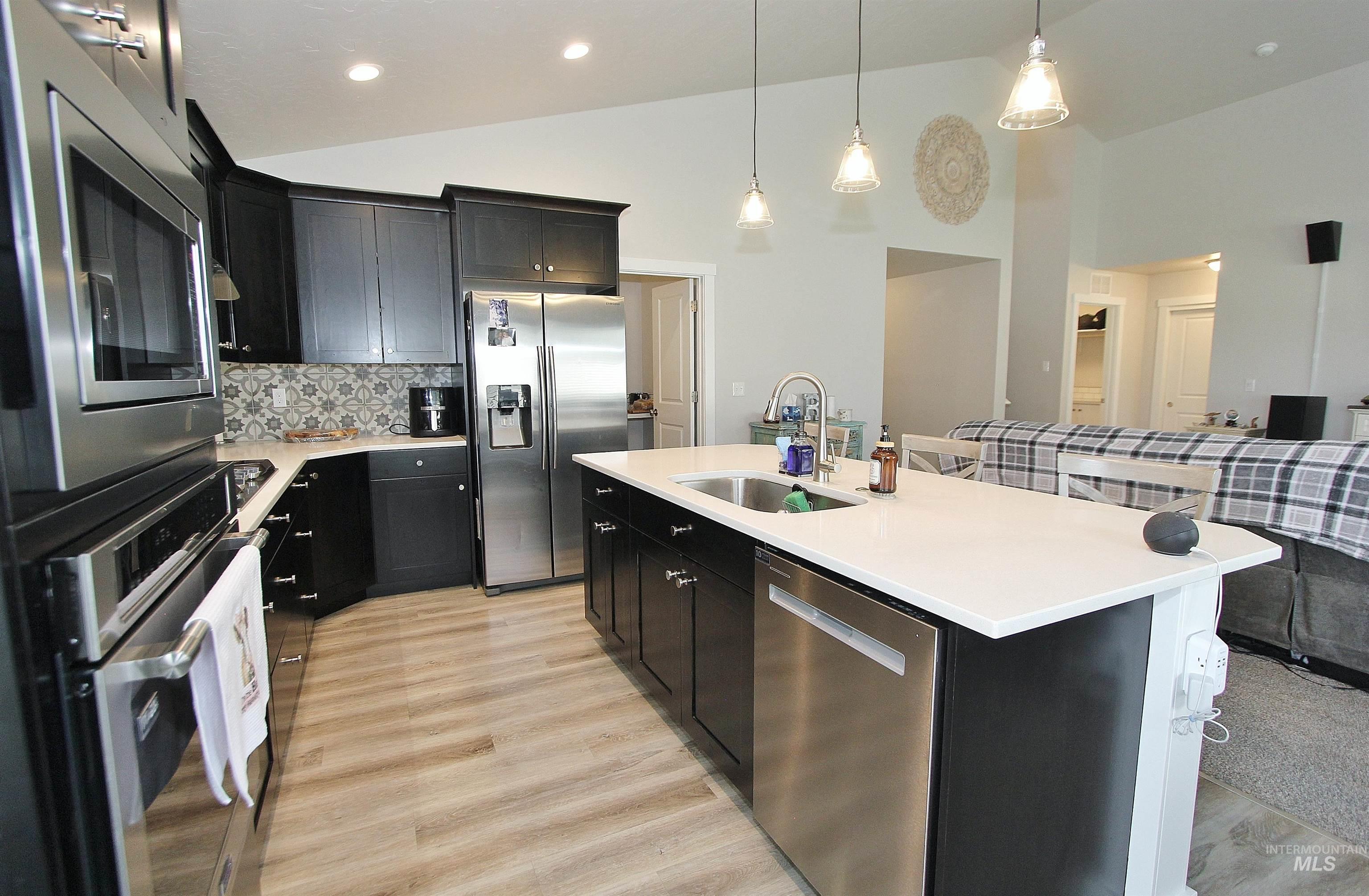 1211 Mahogany Street Parma, ID 83660 - Photo 6 of 22 Kitchen featuring vaulted ceiling, stainless steel appliances, an island with sink, dark cabinets, and a kitchen bar