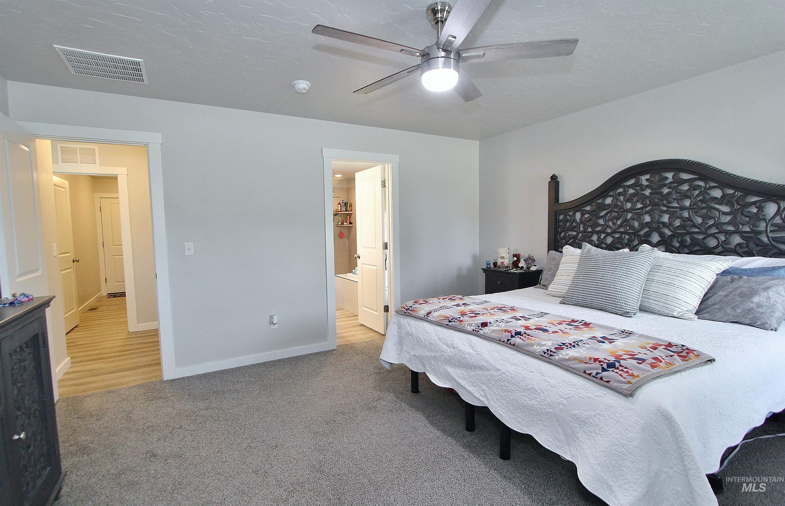 1211 Mahogany Street Parma, ID 83660 - Photo 10 of 22 Bedroom featuring ensuite bathroom, light colored carpet, ceiling fan, and a textured ceiling