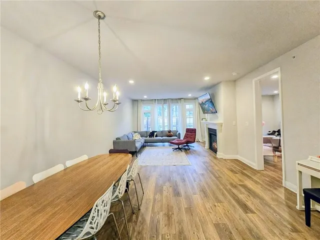a view of a dining room and livingroom with furniture wooden floor a chandelier