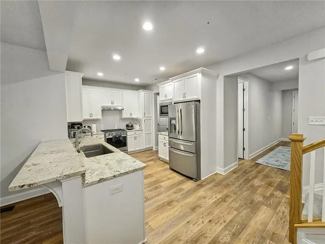 a kitchen with a sink a refrigerator and a stove top oven with wooden floor