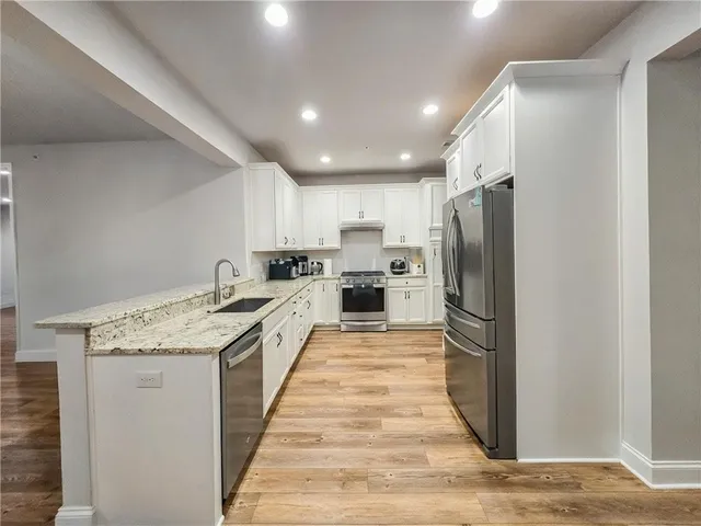 a kitchen with stainless steel appliances granite countertop a refrigerator a stove and a sink