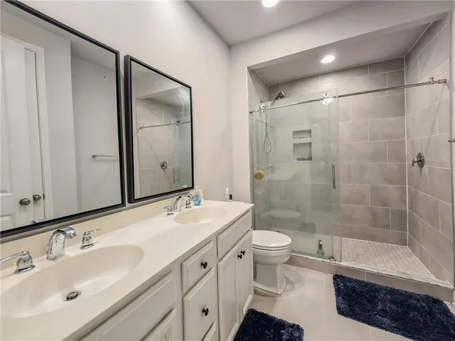 a bathroom with a double vanity sink toilet mirror and shower