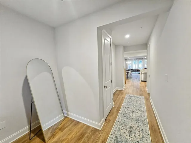 a view of a hallway with wooden floor and a bathroom