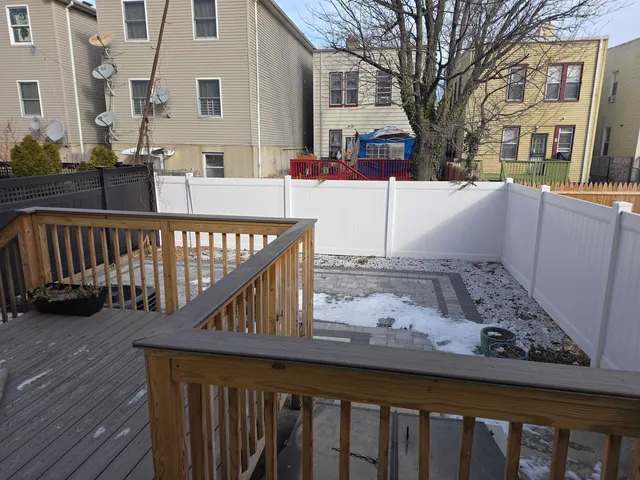 a view of a house with wooden deck and a wooden fence