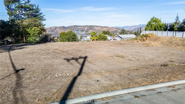 a view of a dry yard with wooden fence