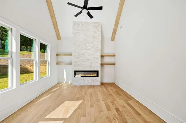 a view of an empty room with wooden floor and a ceiling fan