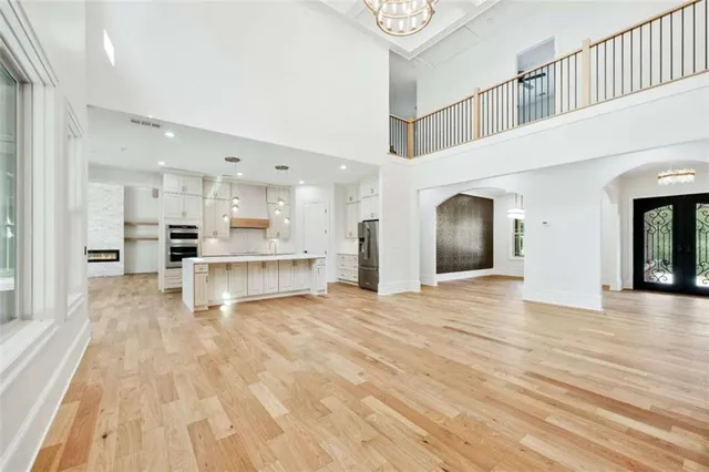 a large kitchen with stainless steel appliances kitchen island granite countertop a large refrigerator a stove and white cabinets with wooden floor